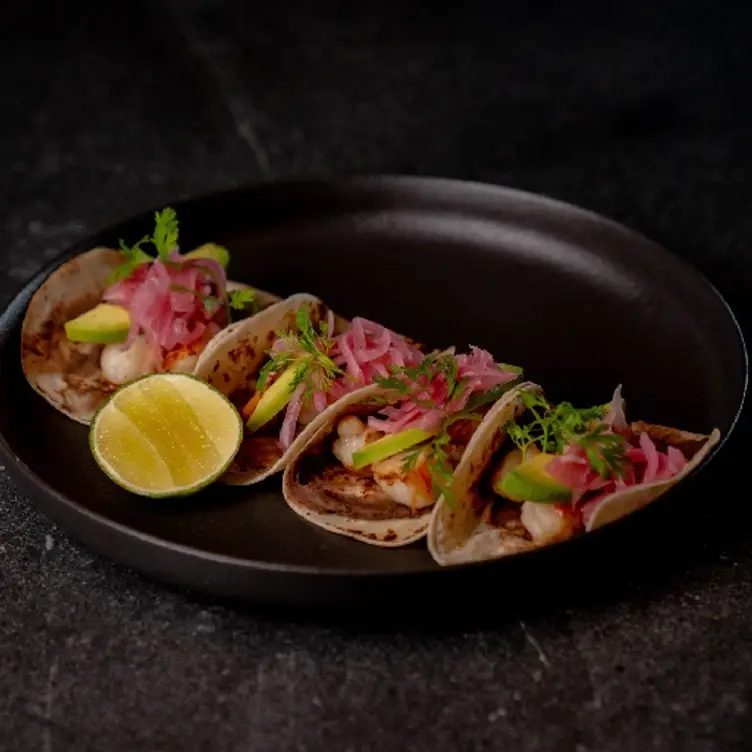 Un plato con cuatro tacos, preparados con cebolla morada, cilantro y una rodaja de limón en Porfirio’s, uno de los mejores restaurantes mexicanos en CDMX.