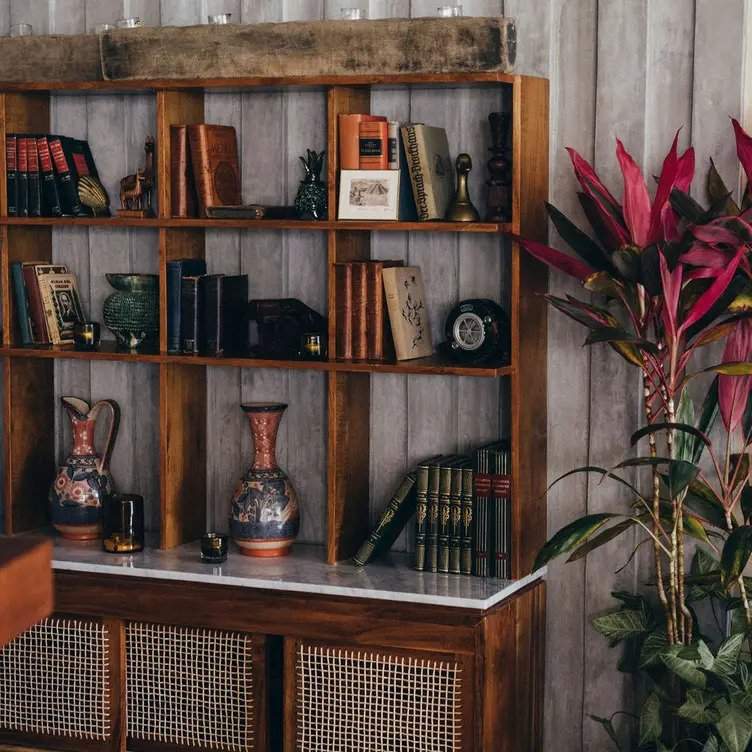 Mueble con libros y objetos decorativos del bar Zapote dentro del Rosewood Mayakoba