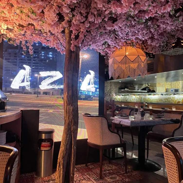 El interior del restaurante Azia, en Polanco, con un árbol de sakura y mesas pequeñas.