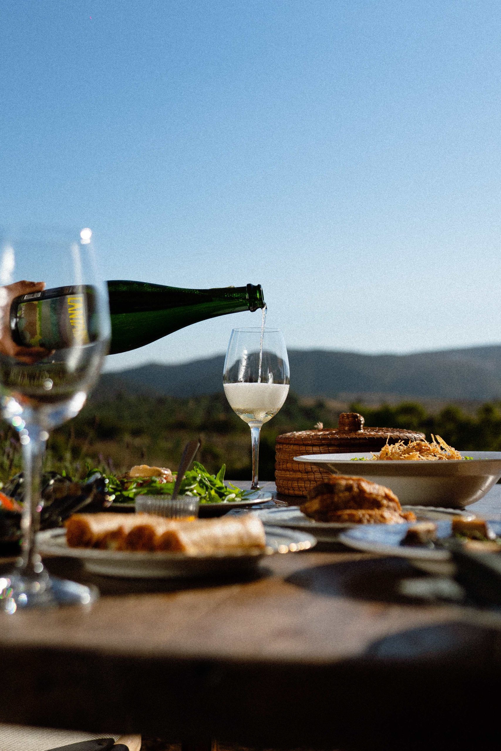 Platillos y una copa de vino servida con el paisaje del Valle como fondo en Villa Torél en el Valle de Guadalupe