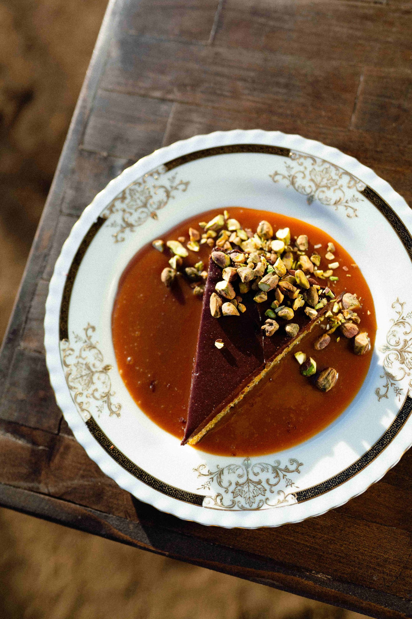 Tarta de chocolate con pistaches por encima servida en un plato de anticuario en Villa Torél en el Valle de Guadalupe