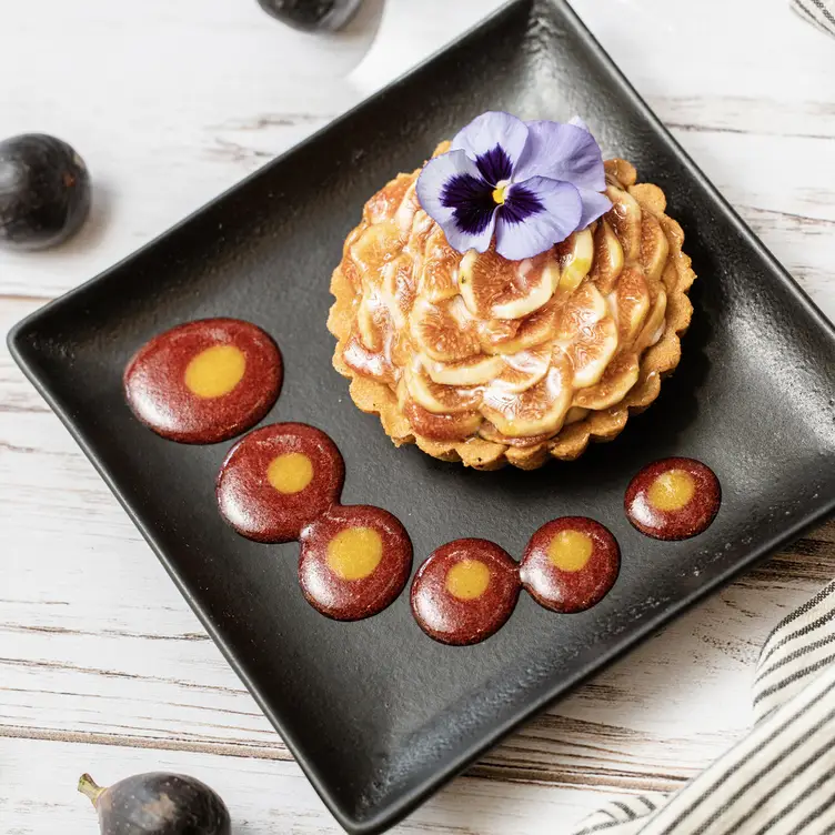 Un postre de Los Canarios compuesto de una deliciosa tarta de frutas decorada con una flor morada.