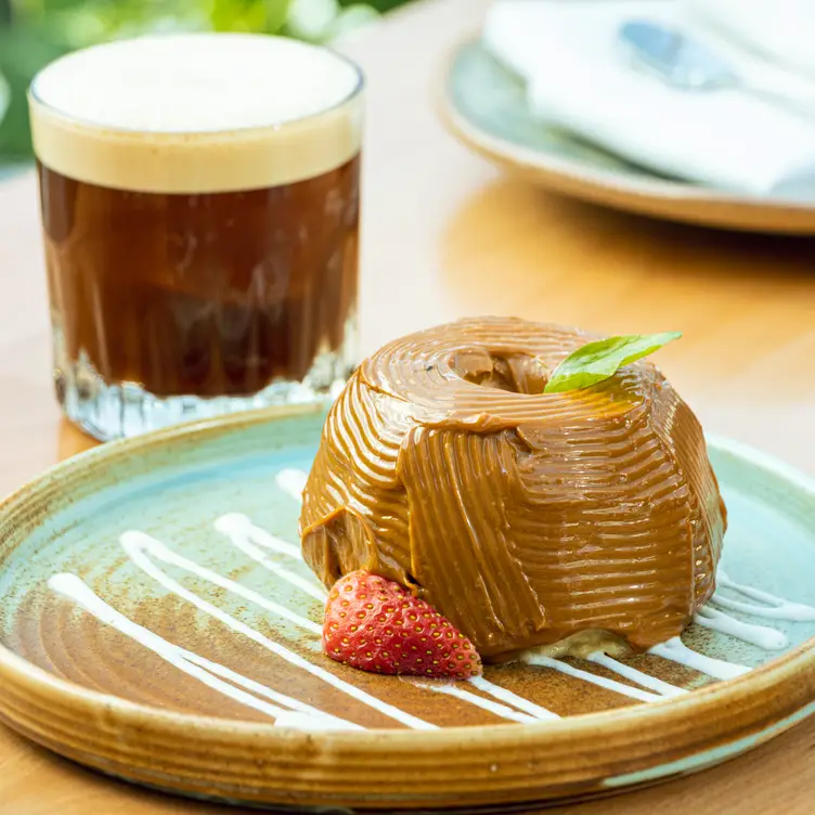 Un plato de postre con una fresa y acompañado por un carajillo en Narú, de los mejores sitios para comer al estilo chino en CDMX.