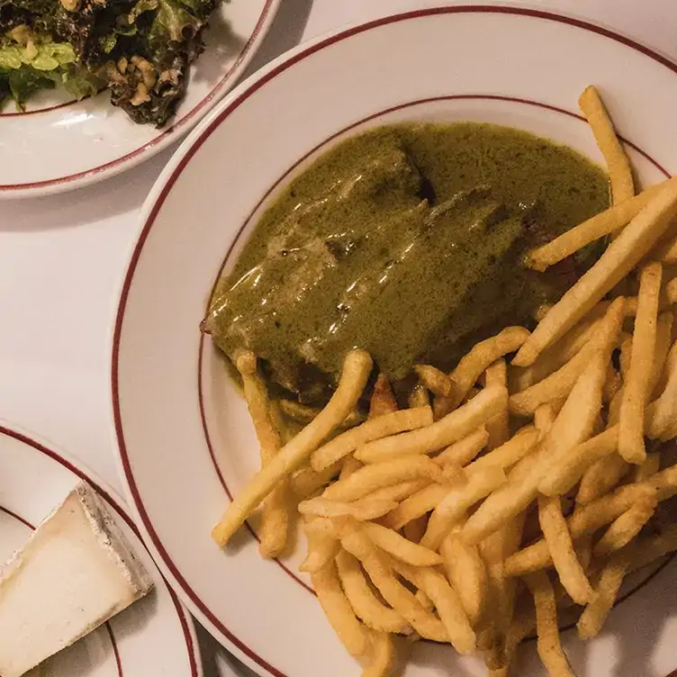 Un filete bañado en salsa de la casa, acompañado con papas fritas en L' Entrecote, uno de los mejores restaurantes para la cena de navidad en la CDMX.