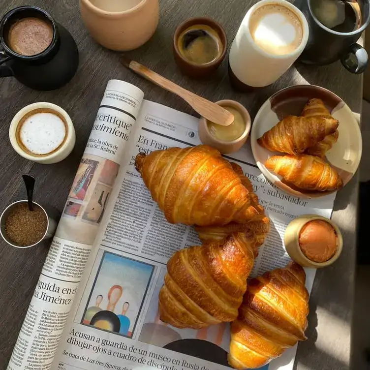 Una variedad de croissants acompañados con salsas y bebidas.