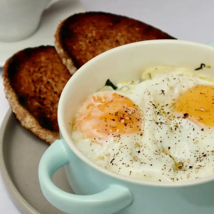 Un platillo compuesto de huevos sazonados con sal y pimienta acompañados de dos rebanadas de pan tostado, parte del menú de Jardín Alba, uno de los mejores restaurantes para desayunar en CDMX