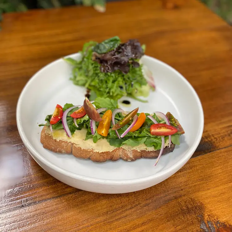 Un pan tostado con hummus y ensalada en Petit Roquefort, uno de los mejores restaurantes veganos en CDMX.