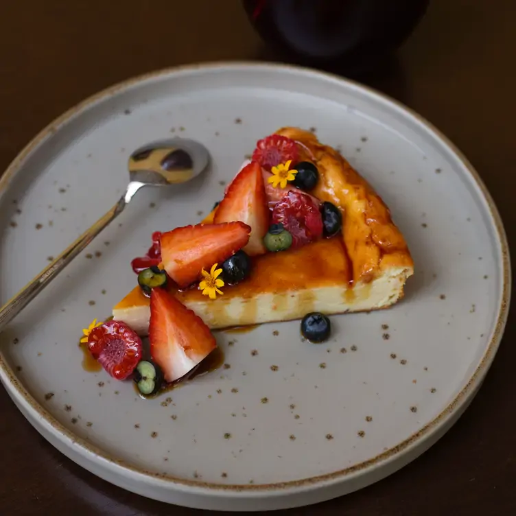 Un pay de queso con uvas, fresas y adornado con flores en Avec Amour - Bistro Fusion.