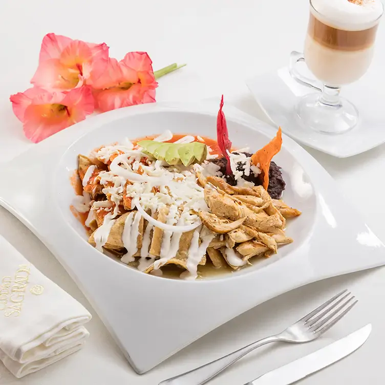 Un plato de chilaquiles con frijoles, crema y queso en Ciudad Sagrada, uno de los mejores restaurantes románticos en Puebla.