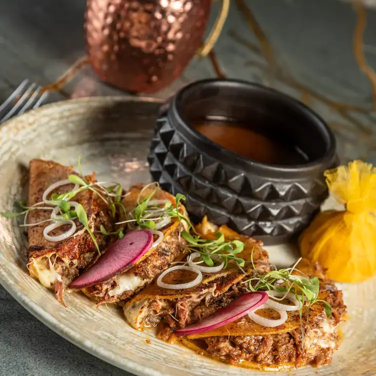 Plato con tacos de birria y salsa en Emplumado, uno de los mejores restaurantes de Mérida.