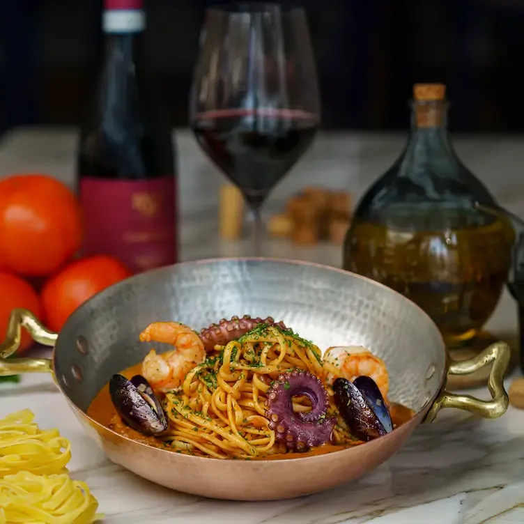 Un bowl de pasta con mariscos acompañado de vino en Cello Cucina Italiana, uno de los mejores restaurantes italianos en Puebla