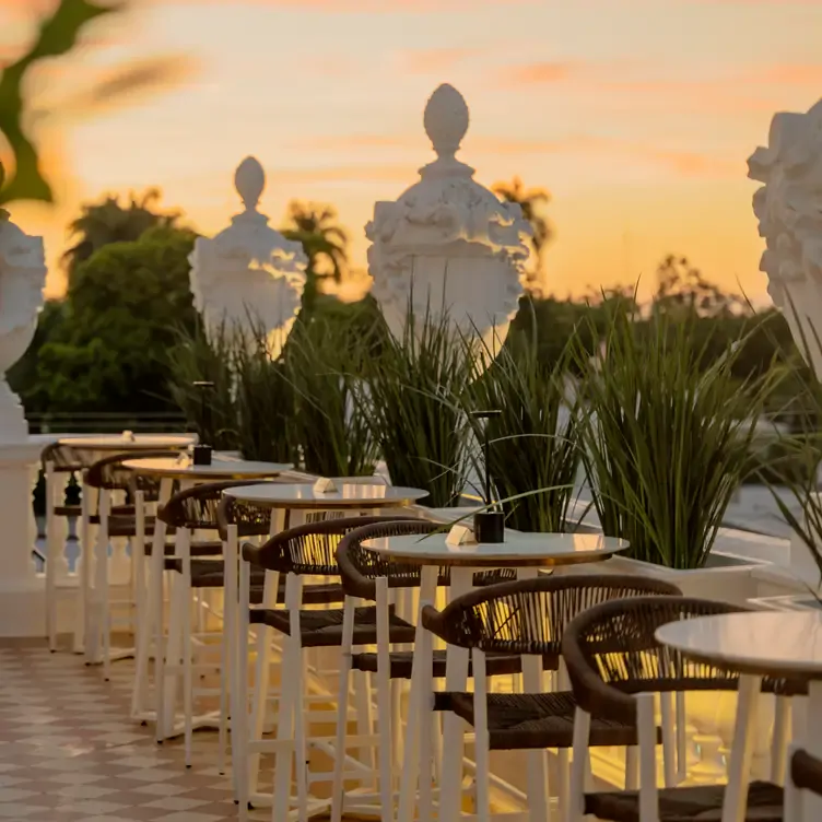 Vista de las mesas blancas de Delina Rooftop al atardecer, de estilo contemporáneo y sillas con acabados cafés.