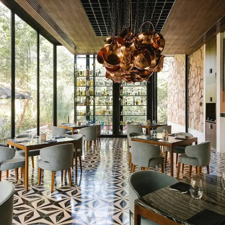 Vista del interior de Ixi'im, uno de los mejores restaurantes románticos en Mérida, con mobiliario elegante y grandes ventanales con vista al entorno natural.