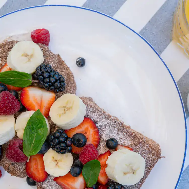 Un pan francés con plátano y frutos rojos en Mandolina, uno de los mejores restaurantes para el brunch en la CDMX