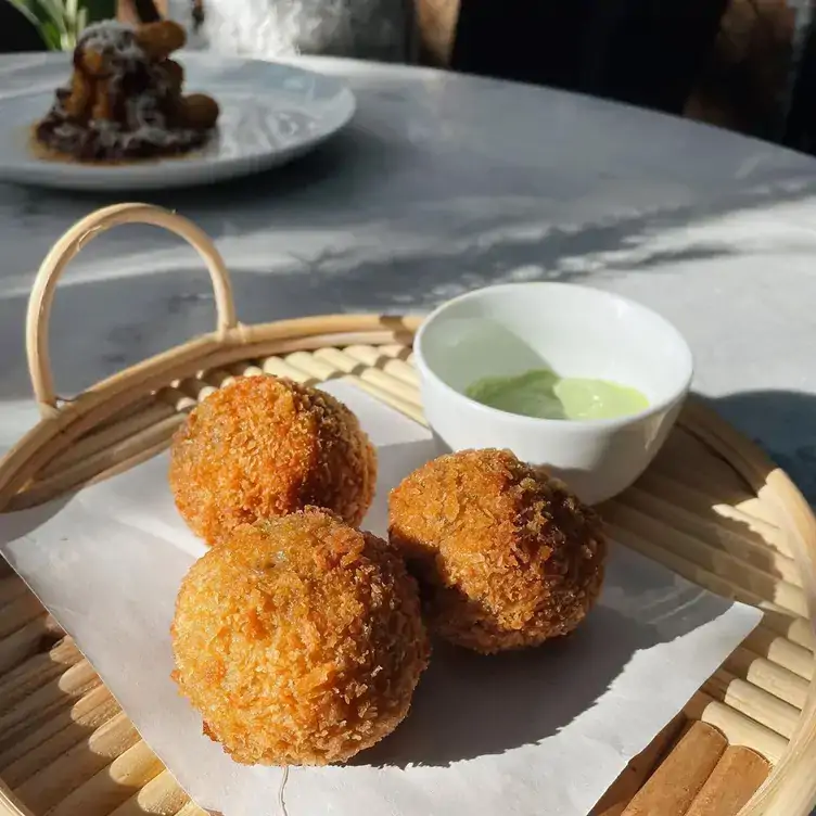 Un plato con tubos de madera que tienen alimentos y salsa de aguacate en Roberta's, una de las mejores opciones que hay en Mérida.