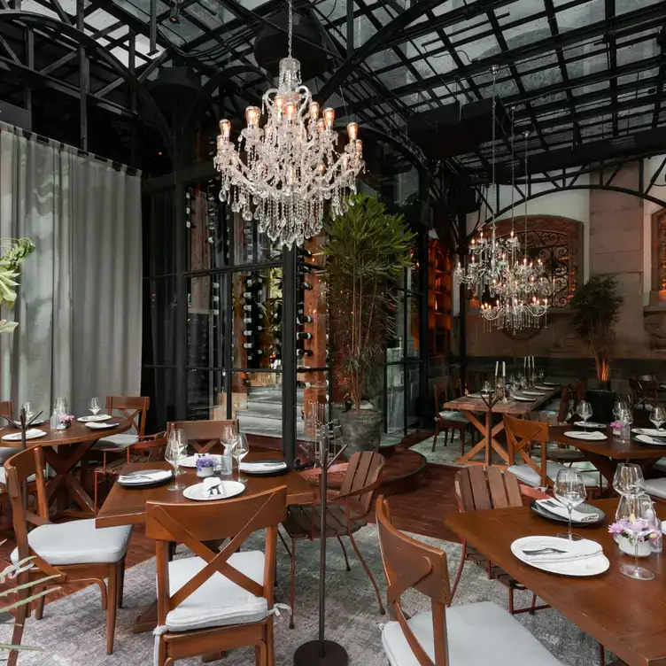 Interior of Parole Polanco, with glass ceiling, hanging chandeliers, wooden furniture and fine glassware on the tables.