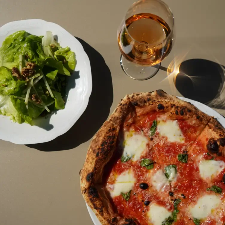 Pizza margherita con un vino blanco y una ensalada verde en Pizzería della Madonna, de las mejores pizzas en CDMX.