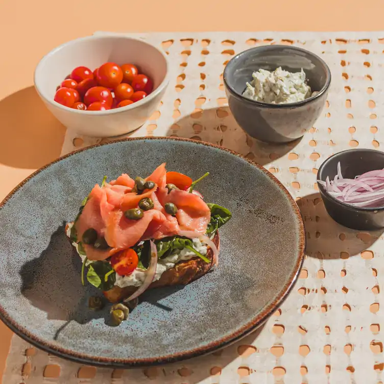 n toast de salmón ahumado con jitomate cherry, tzatziki de queso crema y cebolla morada como guarniciones en Loona Restaurante, uno de los mejores restaurantes para desayunar en Tijuana