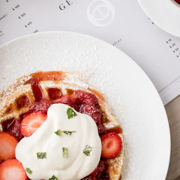 Orden de waffles bañados en mermelada de fresa, decorados con frutos rojos y espolvoreados con azúcar glas en Georgina Restaurante.