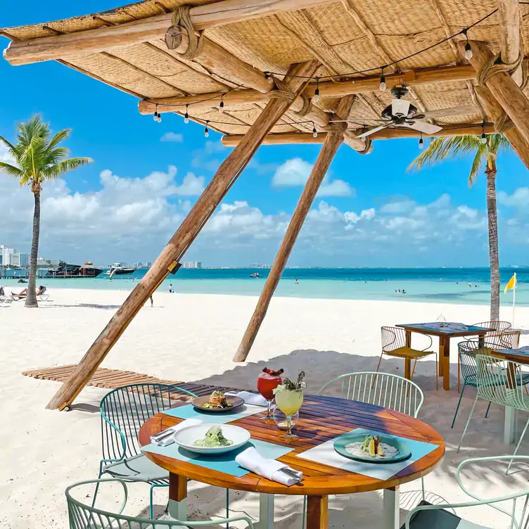 Vista a una mesa a la orilla del mar, servida con platillos de Caribeño Cancún, uno de los mejores restaurantes para desayunar en Cancún.