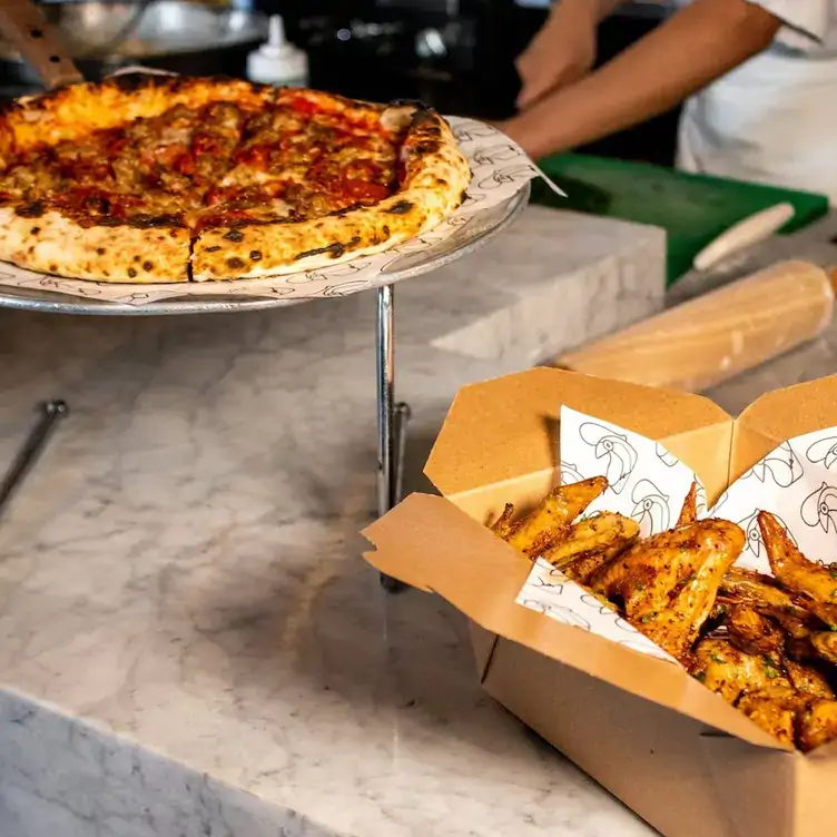 Enfoque en las especialidades de la casa: pizza napolitana preparada en horno de piedra y piezas de pollo orgánico rostizado en Caccio Restaurant, uno de los mejores restaurantes para desayunar en Tijuana.