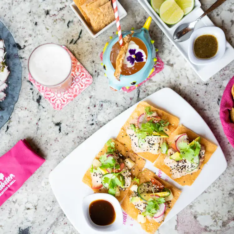 Una mesa con tostadas preparadas, vaso de leche y diversas salsas en Crabster - Paseo 60 Mérida, de los mejores lugares para desayunar en Mérida.