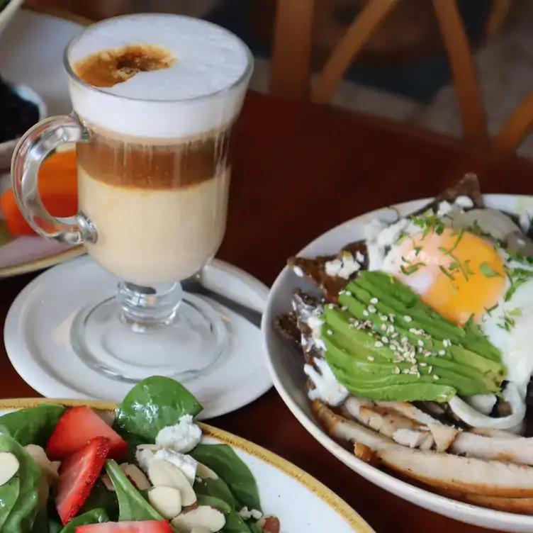 Una mesa con dos platillos y un café capuchino en Marmalade - García Lavín, uno de los mejores desayunos en Mérida.