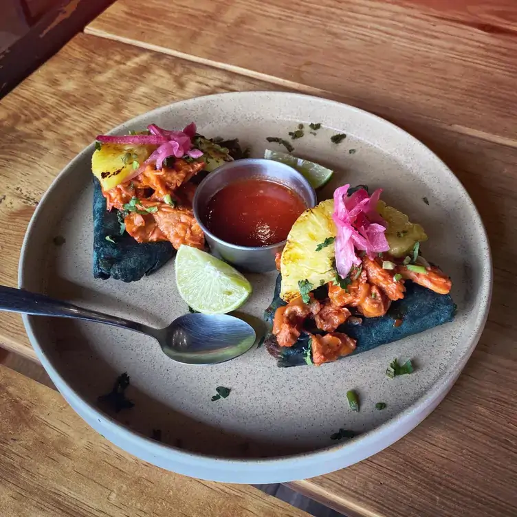 Dos tetelas de maíz azul rellenas de queso, con carne de pastor y piña asada en Maíz Criollo, uno de los mejores restaurantes para desayunar en Puebla