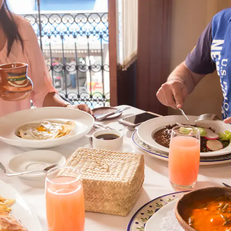 Una pareja desayuna frente a un balcón en El Mural de los Poblanos, uno de los mejores restaurantes para desayunar en Puebla.