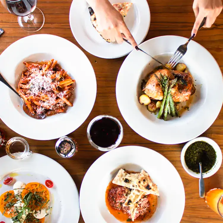 Una variedad de platillos que van de una pasta rigatoni, pollo rôtisserie, ensalada caprese y albóndigas con pan sourdough en Caccio Restaurant.