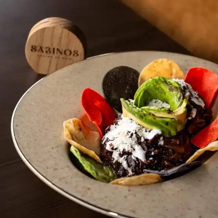 Una tinga de jamaica con queso, crema y aguacate, rodeada con totopos de colores en Sabinos, uno de los mejores restaurantes para desayunar en Puebla.