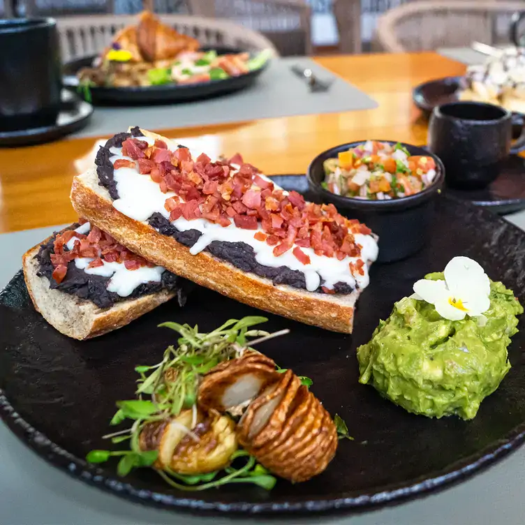 Un par de molletes acompañados con papas al horno estilo curly, guacamole y pico de gallo en Ego Céntrico, uno de los mejores restaurantes para desayunar en Cancún.