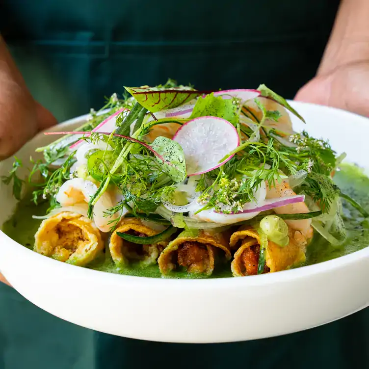 Aguachile de camarón sobre cuatro tacos dorados rellenos de papa y longaniza en Onora.