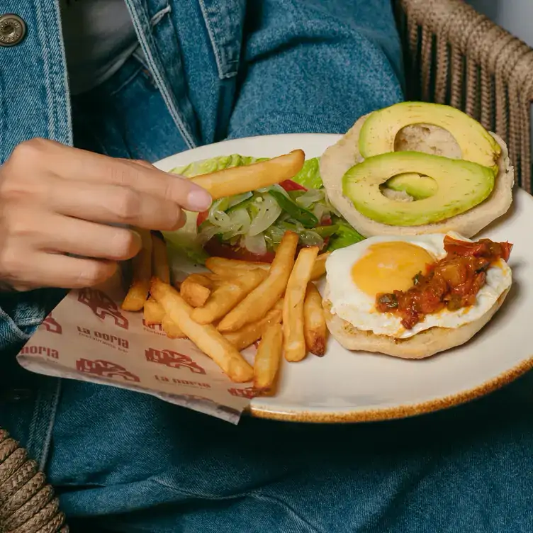 Torta de aguacate y huevo estrellado bañado en salsa, acompañada de ensalada y papas a la francesa en La Noria, uno de los mejores restaurantes para desayunar en Puebla.