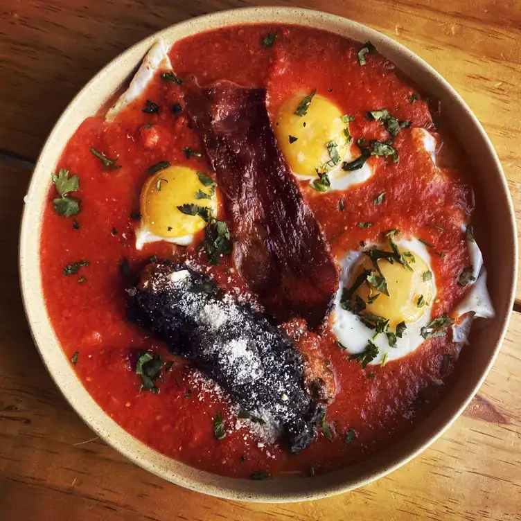 Huevos rancheros bañados en salsa roja, acompañados con tocino y tortillas de maíz fritas en Maíz Criollo, uno de los mejores restaurantes para desayunar en Puebla