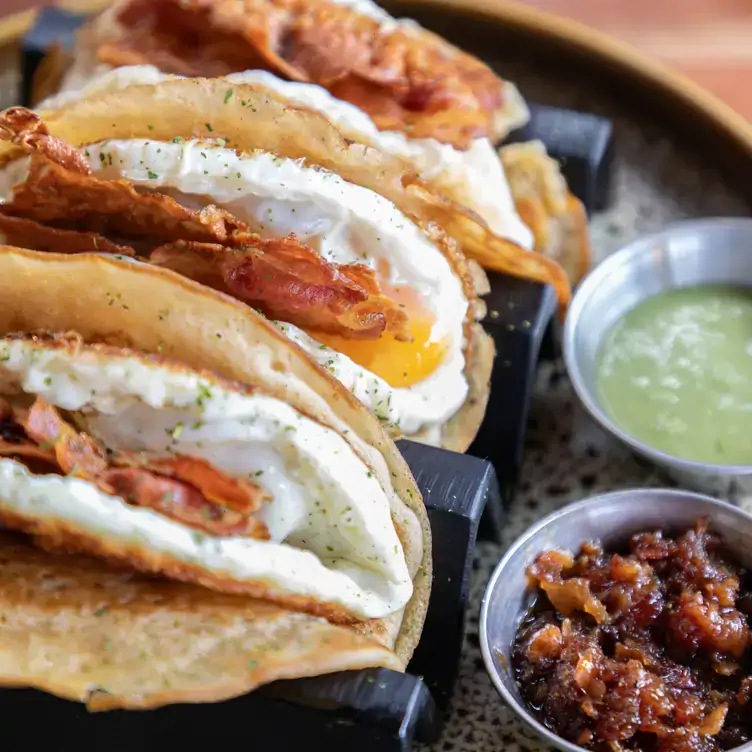 Huevos estrellados montados en tortilla de hot cake, acompañados de tocino fresco y mermelada de chicharrón prensado en KAALAU, uno de los mejores restaurantes para desayunar en Cancún.