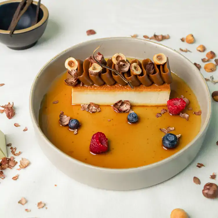 Flan de vainilla decorado con dulce de leche, frutos rojos y nueces en Leynia, uno de los mejores restaurantes para el brunch en Cancún.