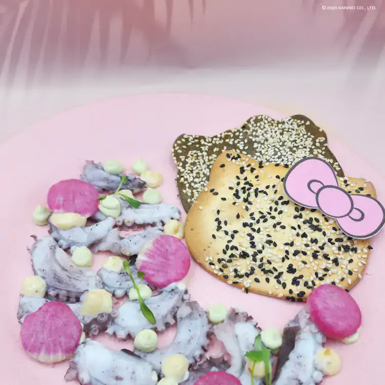 Platillo de pulpo con granos de elote, acompañado de dos tostadas con ajonjolí en la forma del rostro de Hello Kitty®.