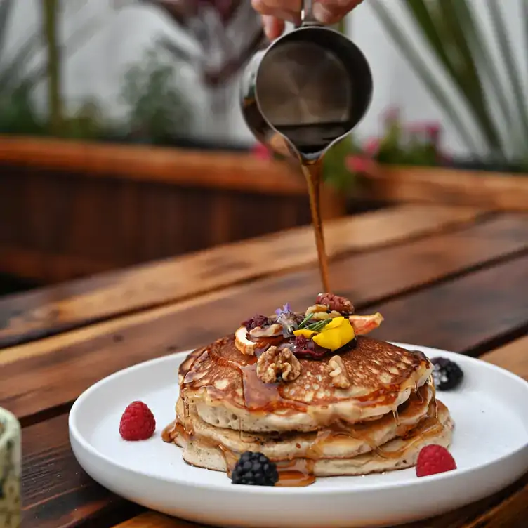 Tres hot cakes bañados en miel de maple, decorados con nuez y frutos rojos en Casa Rey, uno de los mejores restaurantes para desayunar en Tijuana.