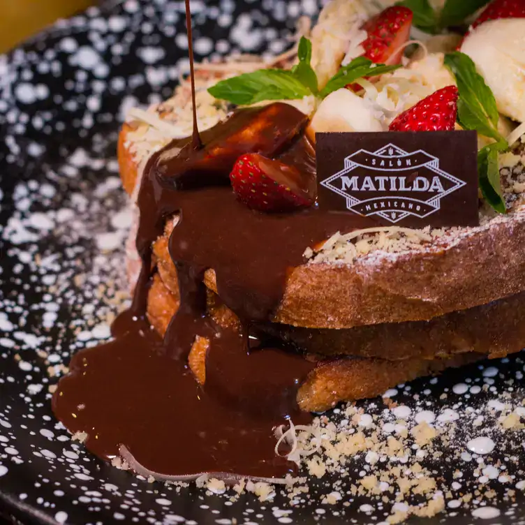 Pan servido con queso, fresas y chocolate líquido en Matilda Salón Mexicano.