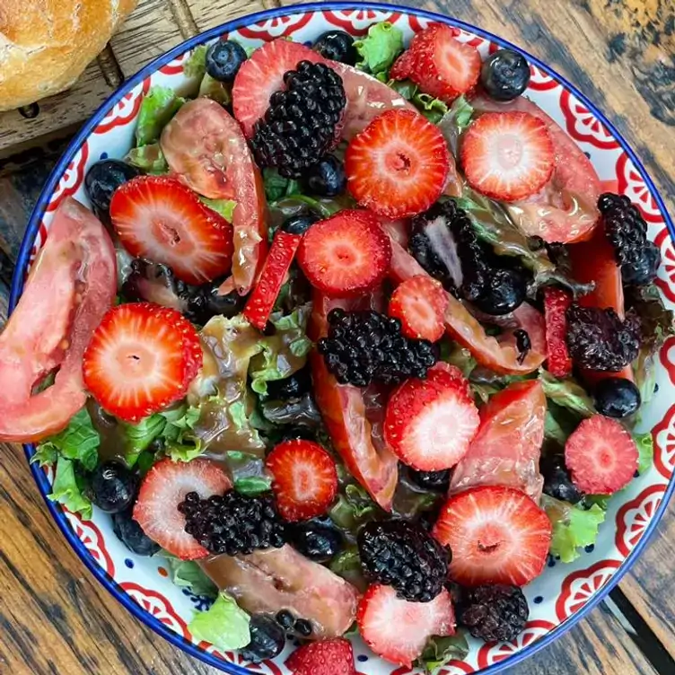 Un plato colorido con diversos vegetales como lechuga, jitomate, zarzamora, fresa y arándano.