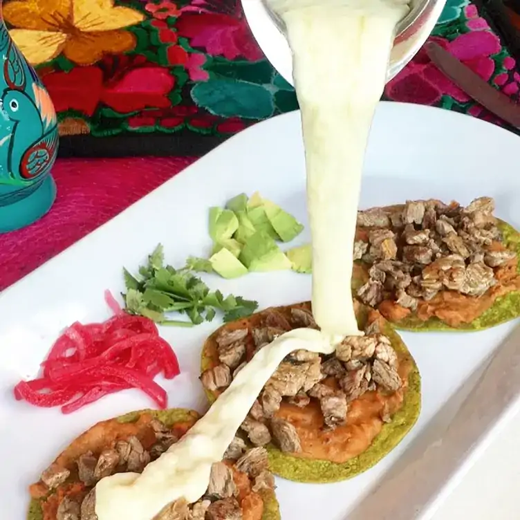 Tres tostadas de nopal servidas con arrachera picada sobre una cama de frijoles diablo en Chepil Cocina Mexicana.