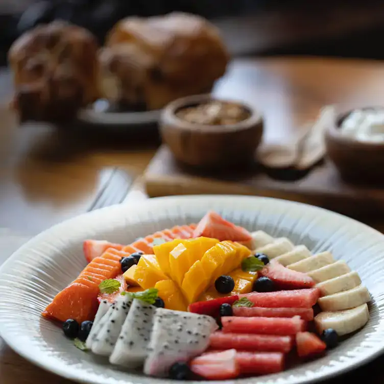 Una mesa con un plato de frutas y pan al fondo en Jumiles Experiencia Mexicana, una de las mejores opciones para el brunch en Mérida.