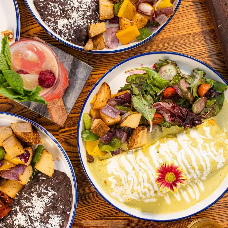 Un omelette en salsa verde con ensalada y papas al horno como guarnición, acompañado de la mixología de Casa Rey, uno de los mejores restaurantes para desayunar en Tijuana.