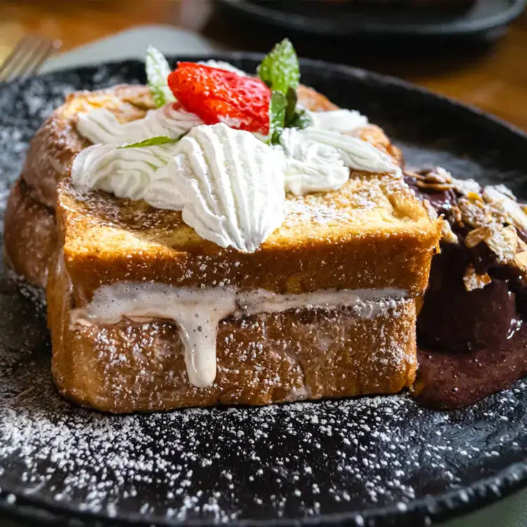 Pan francés decorado con crema batida y fresas frescas, acompañadas de helado con nueces en Ego Céntrico, uno de los mejores restaurantes para el brunch en Cancún.