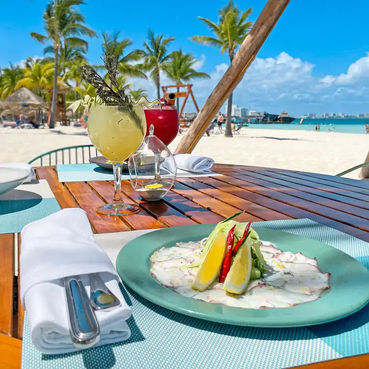 Un par de cocteles y platillos a la orilla del mar en Caribeño Cancún, uno de los mejores restaurantes para desayunar en Cancún.