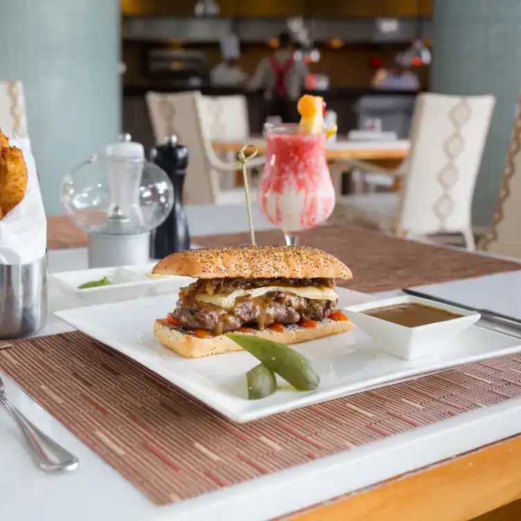 Una mesa servida con una baguette de carne, bebidas y decoración moderna en Burger at Vidanta Vallarta.