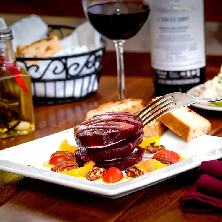 Una tapa servida con una copa de vino sobre una mesa de madera en Barcelona Tapas - Puerto Vallarta, una de las mejores opciones para comer en Puerto Vallarta.