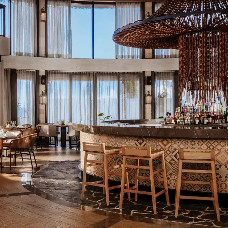 A wooden central bar with a high centrepiece and glass windows at Quinto at Vidanta Riviera Maya in Playa del Carmen