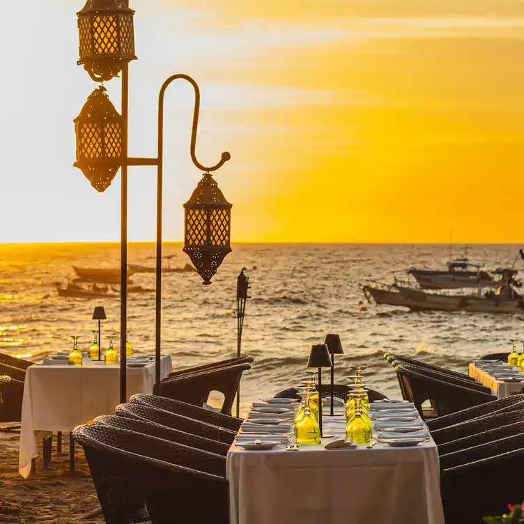 Vista de las mesas exteriores a la orilla del mar en un atardecer en La Palapa Restaurant, uno de los mejores restaurantes románticos en Puerto Vallarta.